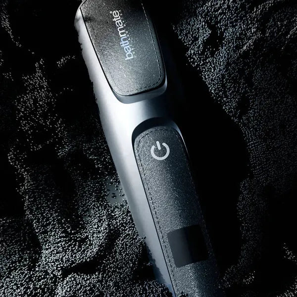 Bathmate Trim 2.0 kroppstrimmer i matt sort design med rustfrie stålblader og strømknapp, plassert på en teksturert overflate.