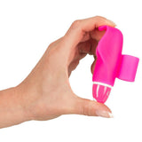 En hånd holder en liten, rosa delfinformet klitorisvibrator i silikon med hvite detaljer.