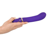 Hånd holder en lilla, silkemyk G-punkts vibrator med gullfarget detalj og kontrollknapper.