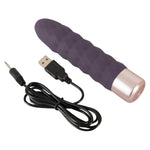 Lilla silikon klitorisvibrator med bølget tekstur og rosegull base, med USB-ladekabel.