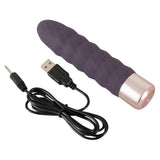 Lilla silikon klitorisvibrator med bølget tekstur og rosegull base, med USB-ladekabel.