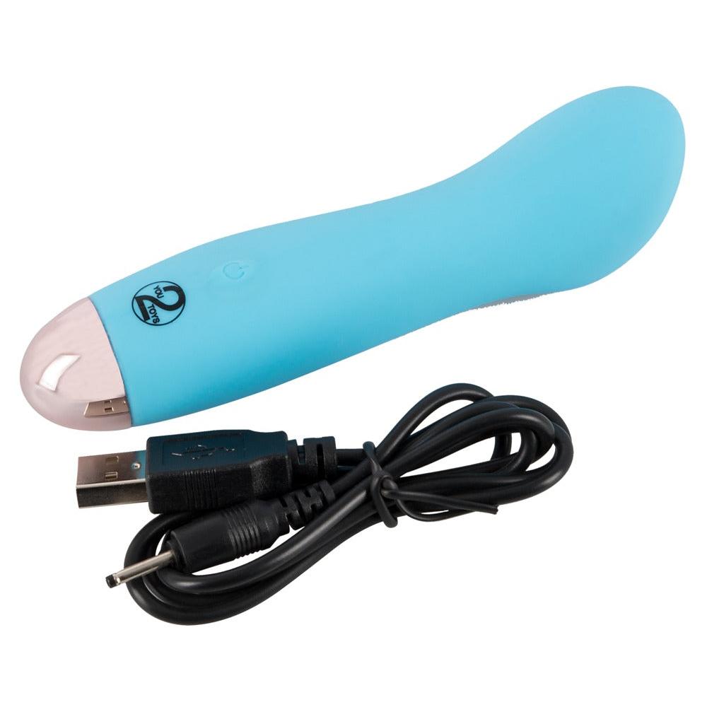 Liten, silkemyk blå klitorisstimulator med buet tupp og USB-ladekabel.
