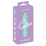 Turkis Cuties minivibrator i silkemyk silikon med rillet overflate, vist i lilla emballasje.