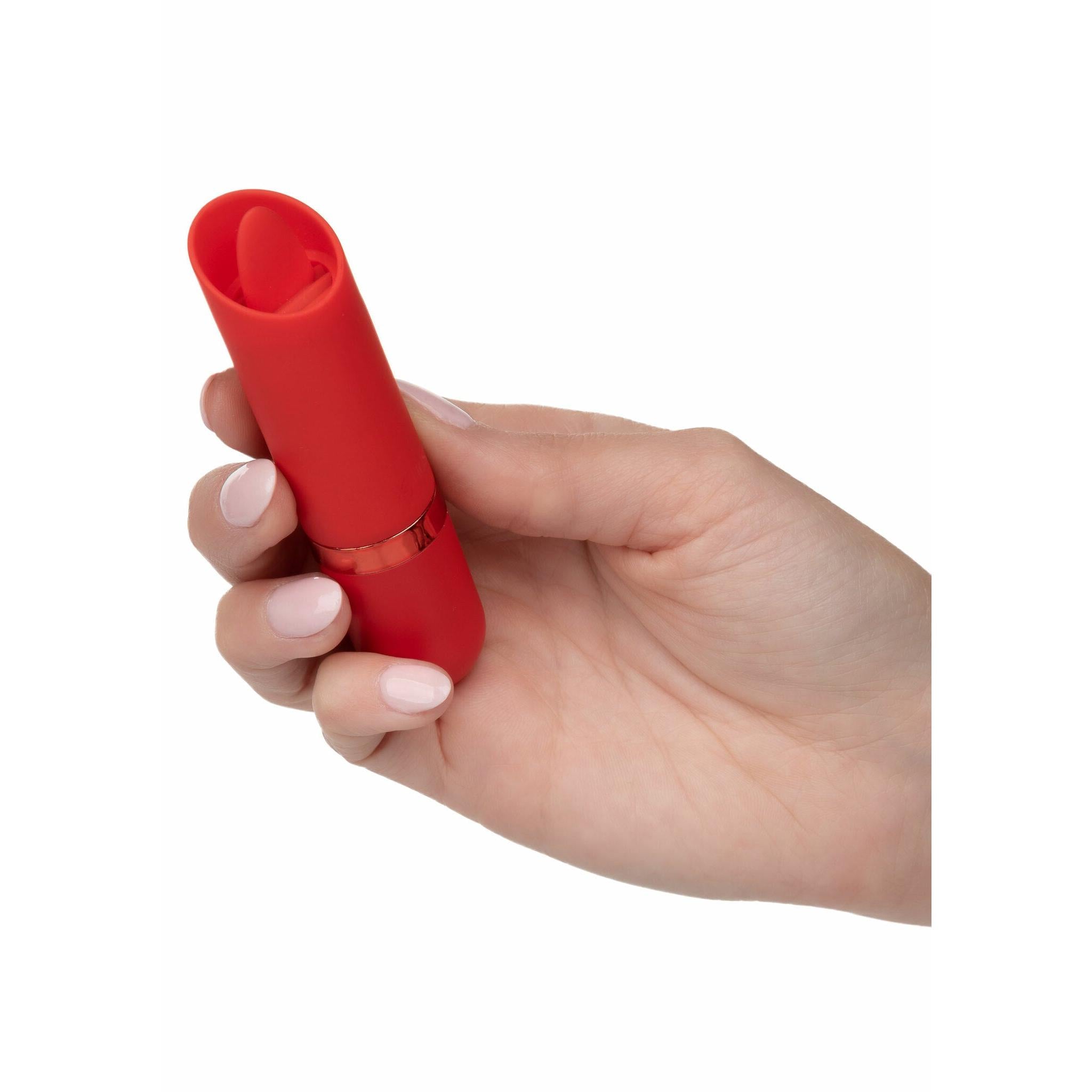 Hånd holder en rød Kyst Flicker klitorisvibrator i fløyelsmyk silikon med tungefunksjon og gullring.