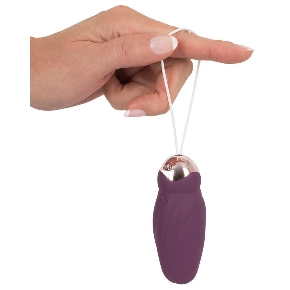 Javida Rotating Love Ball, et lilla silikon vibrerende egg med gullfarget topp og hvit hentesnor, holdt av en hånd.