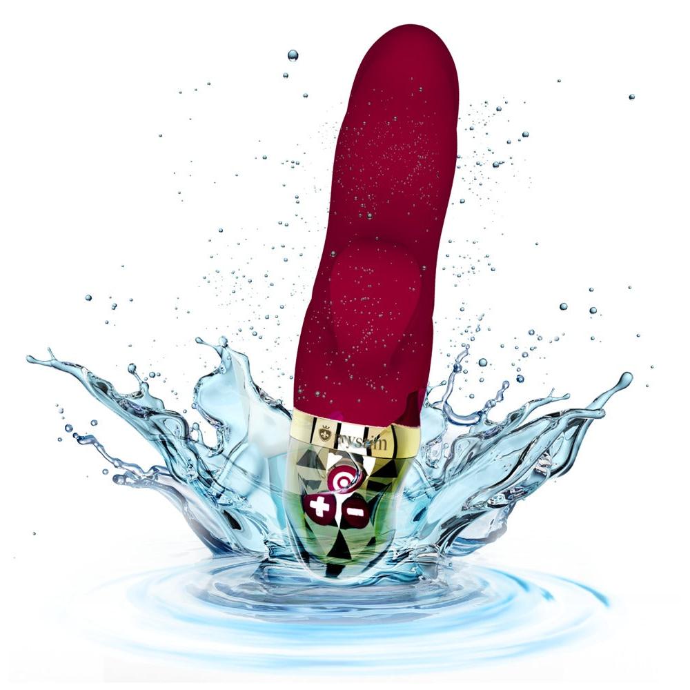 Rød silikon rabbitvibrator med gullfarget base og kontrollknapper, omgitt av vannsprut.