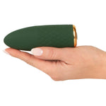 Grønn, kompakt mini vibrator med rutemønster og gullfarget base, holdt i en hånd.