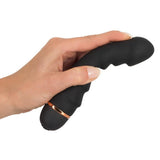 En hånd holder en svart silikon vibrator med penisformet tupp, 5 bølger og kobberfarget ring.