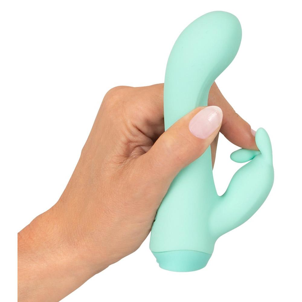 Hånd holder en mintgrønn Cuties Little Rabbit vibrator i silkemyk silikon med dobbel stimulering.