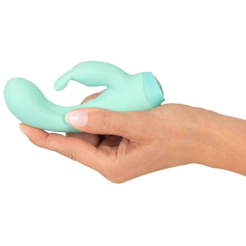 En hånd holder en mintgrønn Cuties Little Rabbit vibrator i silkemyk silikon.