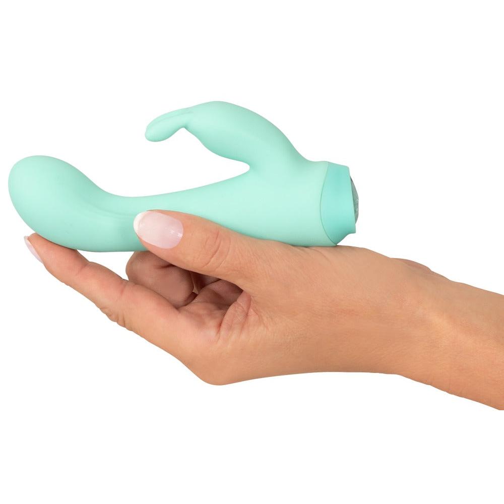 En hånd holder en mintgrønn Cuties Little Rabbit vibrator i silkemyk silikon.