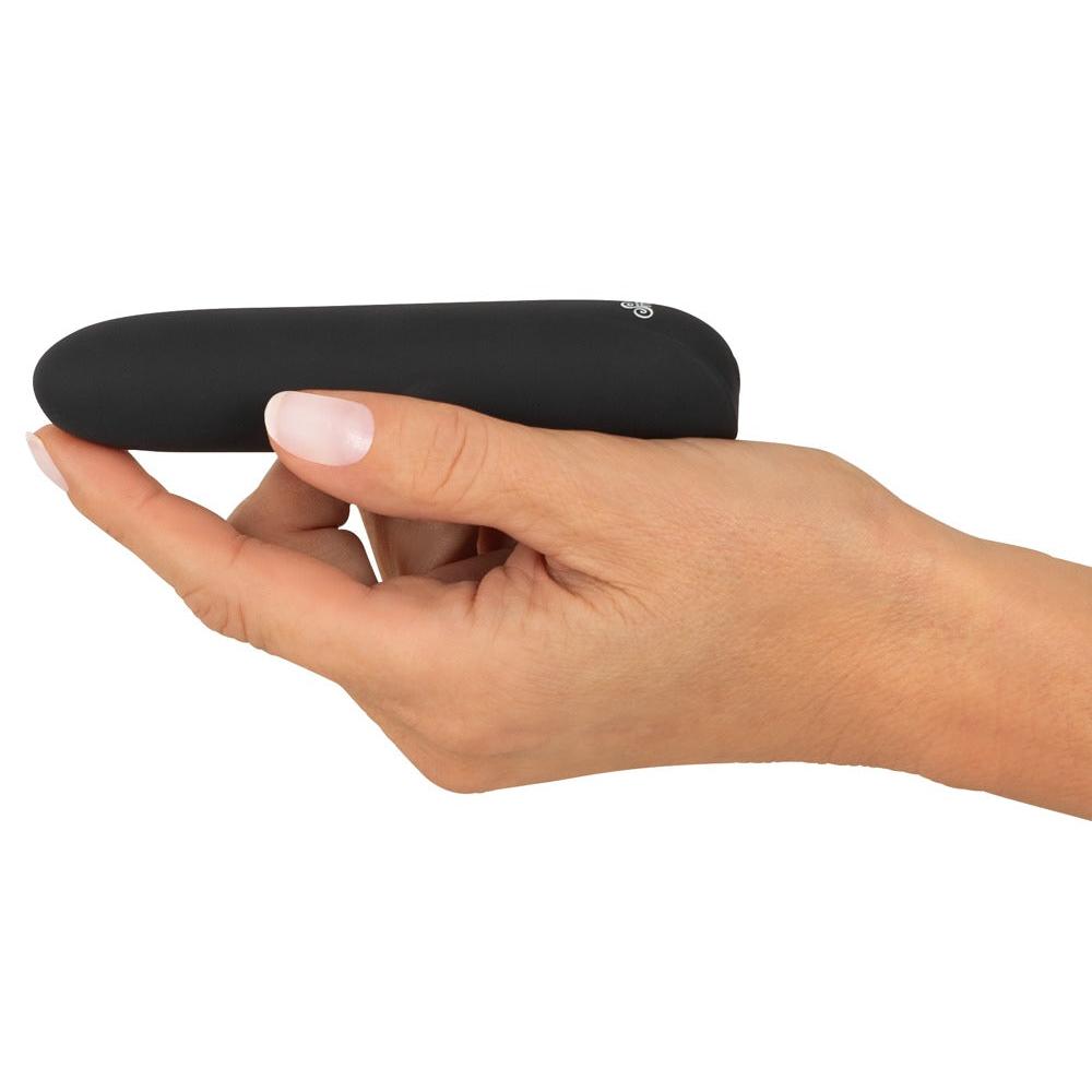En hånd holder en liten, svart, silikon Sweet Smile klitorisvibrator med diskrete knapper.