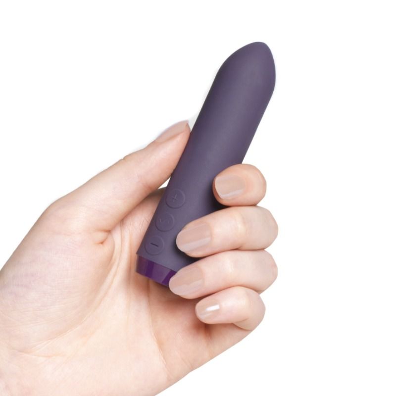 Hånd holder en mørk lilla, matt silikon Je Joue Klassisk Bullet Vibrator med kontrollknapper.