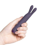 Hånd holder en lilla Je Joue Rabbit Bullet vibrator i silkemyk silikon med to fleksible ører.