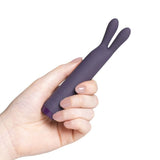 Hånd holder en lilla Je Joue Rabbit Bullet vibrator i silkemyk silikon med to fleksible ører.