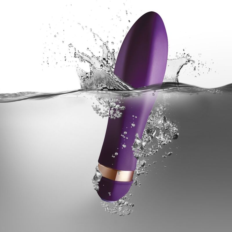 Lilla Twister klitorisvibrator i kroppssikker silikon med gullring, delvis nedsenket i vann.
