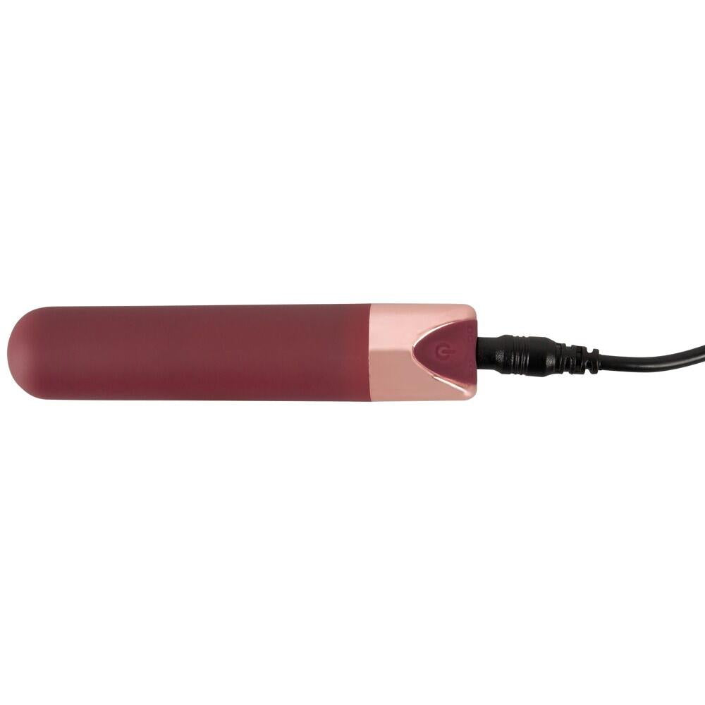 Mørkerød bullet-vibrator med rosegull-detaljer og ladekabel tilkoblet.