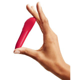 En hånd holder en liten, rød We-Vibe Tango X klitorisstimulator med spiss ende.
