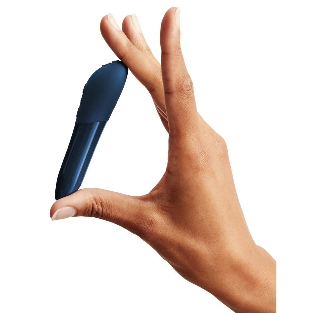 En hånd holder en liten, elegant blå We-Vibe Tango X klitorisvibrator i silikon.