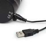 Svart HappyRabbit realistisk vibrator med USB-ladekabel tilkoblet, klar for lading.