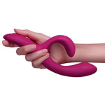 Hånd holder en fleksibel, fuchsia We-Vibe Nova 2 rabbitvibrator i silkemyk silikon.