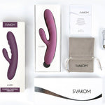 Dyp lilla Avery rabbitvibrator fra SVAKOM, i og utenfor esken, med ladeledning og oppbevaringspose.