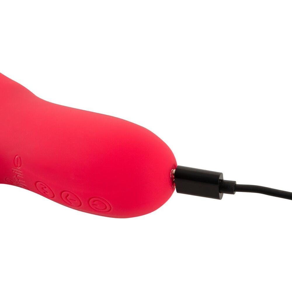 Rød silikon rabbitvibrator med dunkende funksjon, tilkoblet svart magnetisk USB-ladekabel.