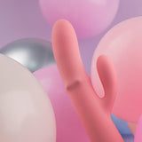 Rosa SVAKOM Mora Neo rabbitvibrator i silikon med dobbel stimulering, omgitt av pastellfargede ballonger.