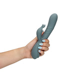 Hånd holder en grå Loveline Rabbitvibrator i silikon med fingerlignende stimulator og kontrollknapper.