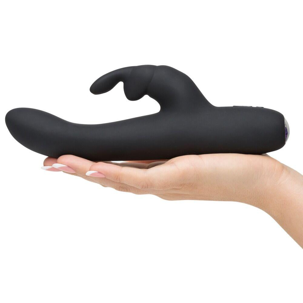 Greedy Girl Slimline Rabbit Vibrator i svart silikon, holdt i en hånd, med buet form og kaninører.