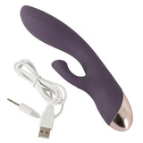 Lilla silikon rabbitvibrator med klitorissuger, buet G-punkt skaft, gullfarget base og hvit USB-ladekabel.