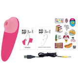 ROMP Shine X lufttrykksvibrator i rosa silikon, med ladekabel, manualer og klistremerker.
