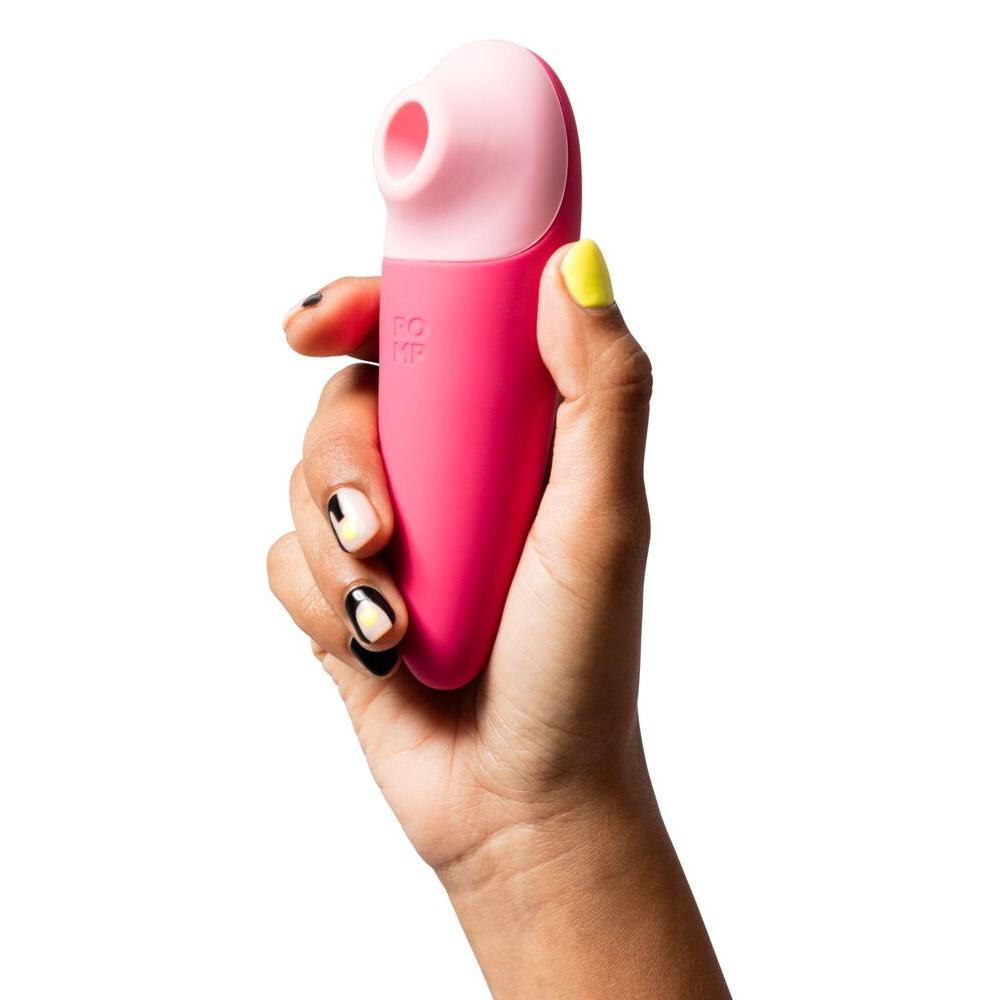 Hånd holder en kompakt, rosa ROMP Shine X lufttrykksvibrator med lyserosa munnstykke.
