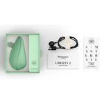 Womanizer Liberty 2 sugevibrator i myk mintgrønn, med USB-lader og instruksjoner i åpen eske.