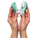 Hender holder en mintgrønn Womanizer Liberty 2 sugevibrator med magnetisk deksel og hvit silikonmunnstykke.
