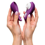 Hender holder en lilla Womanizer Liberty 2 sugevibrator med hvitt munnstykke og matchende magnetdeksel.