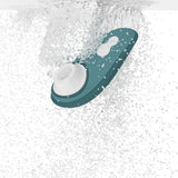 Mørkegrønn Womanizer Liberty 2 sugevibrator med hvitt munnstykke, nedsenket i vann.