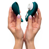 To hender holder en mørkegrønn Womanizer Liberty 2 sugevibrator med magnetdeksel.