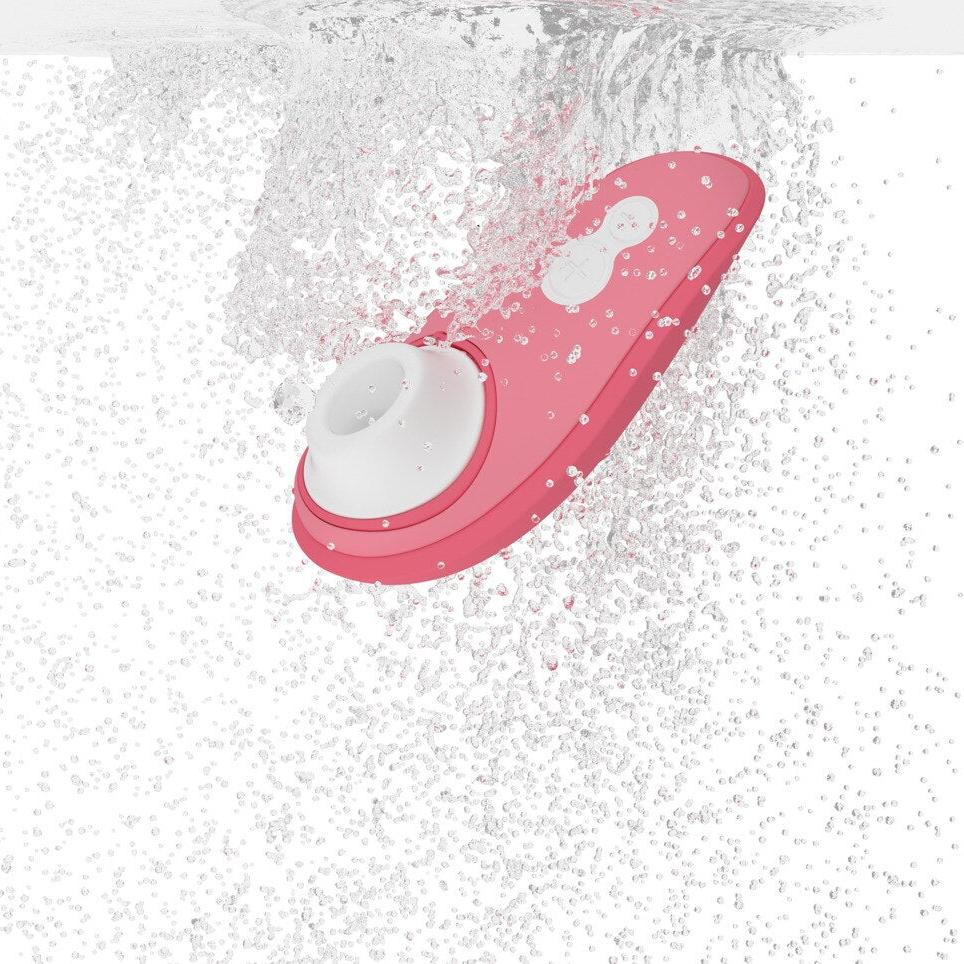 Womanizer Liberty 2 i korallrosa, vanntett sugevibrator med hvitt munnstykke, nedsenket i vann.