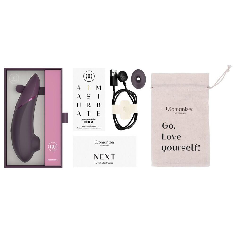 Lilla Womanizer NEXT sugevibrator i eske med tilbehør, ladekabel og oppbevaringspose.
