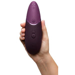 Womanizer NEXT sugevibrator i elegant lilla med Soft Touch-overflate, holdt i en hånd.