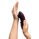 Womanizer NEXT sugevibrator i lilla med Soft Touch-overflate, holdt i hender.