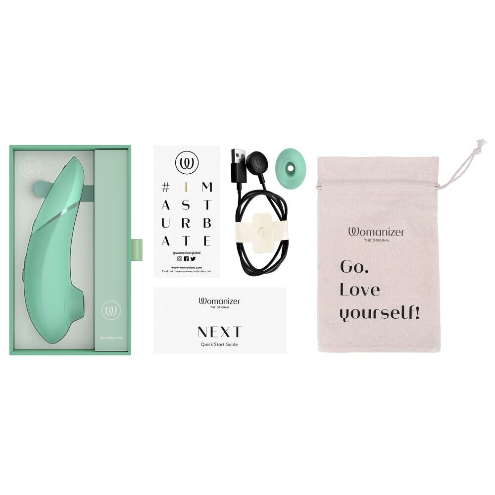 Mintgrønn Womanizer NEXT sugevibrator i åpen eske med lader, munnstykke, og oppbevaringspose.