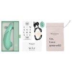 Mintgrønn Womanizer NEXT sugevibrator i åpen eske med lader, munnstykke, og oppbevaringspose.