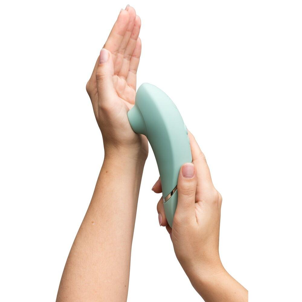 Kvinne holder en Womanizer NEXT sugevibrator i mintgrønn med Soft Touch-overflate.