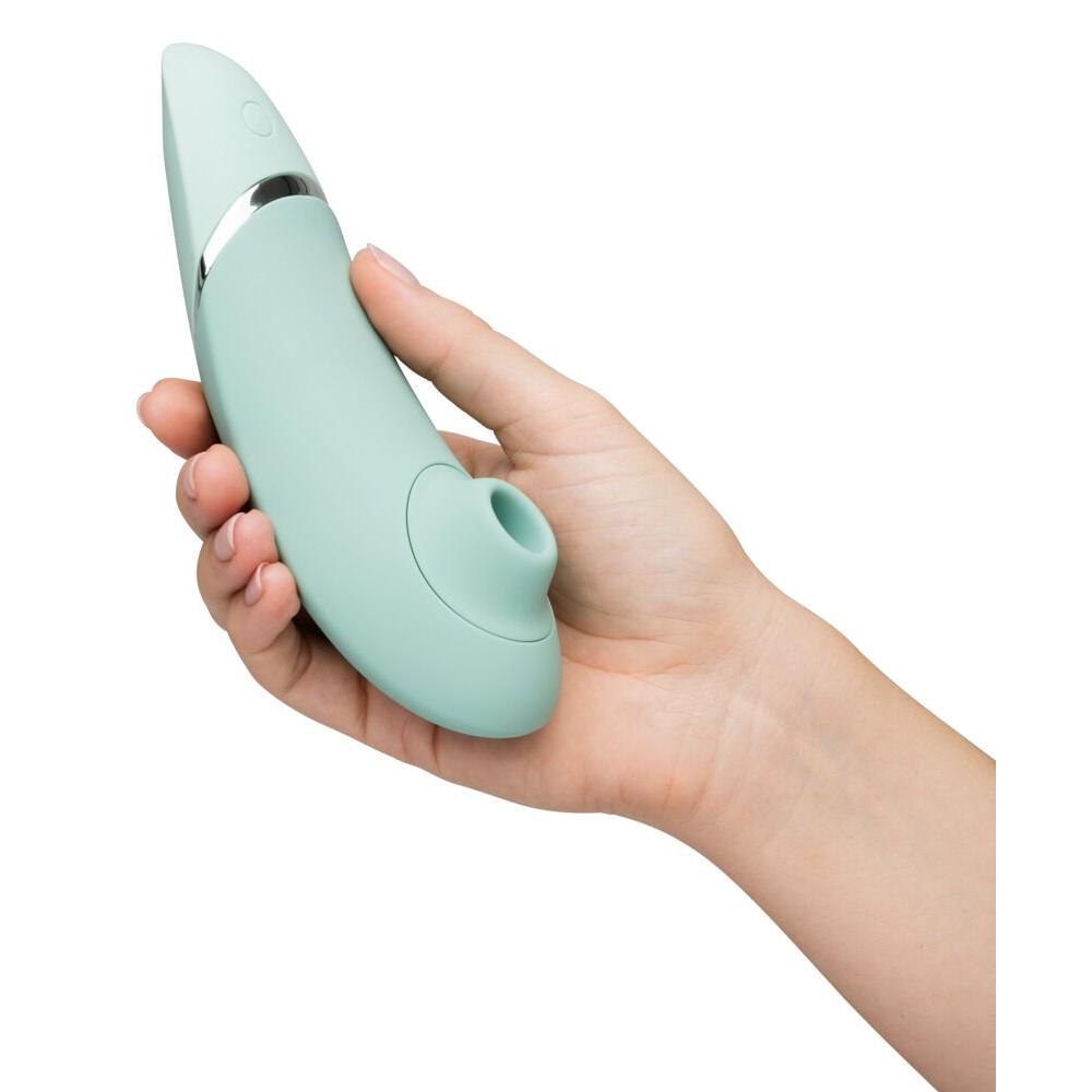 Womanizer NEXT i mintgrønn med Soft Touch-overflate, holdt i en hånd, viser slank design.