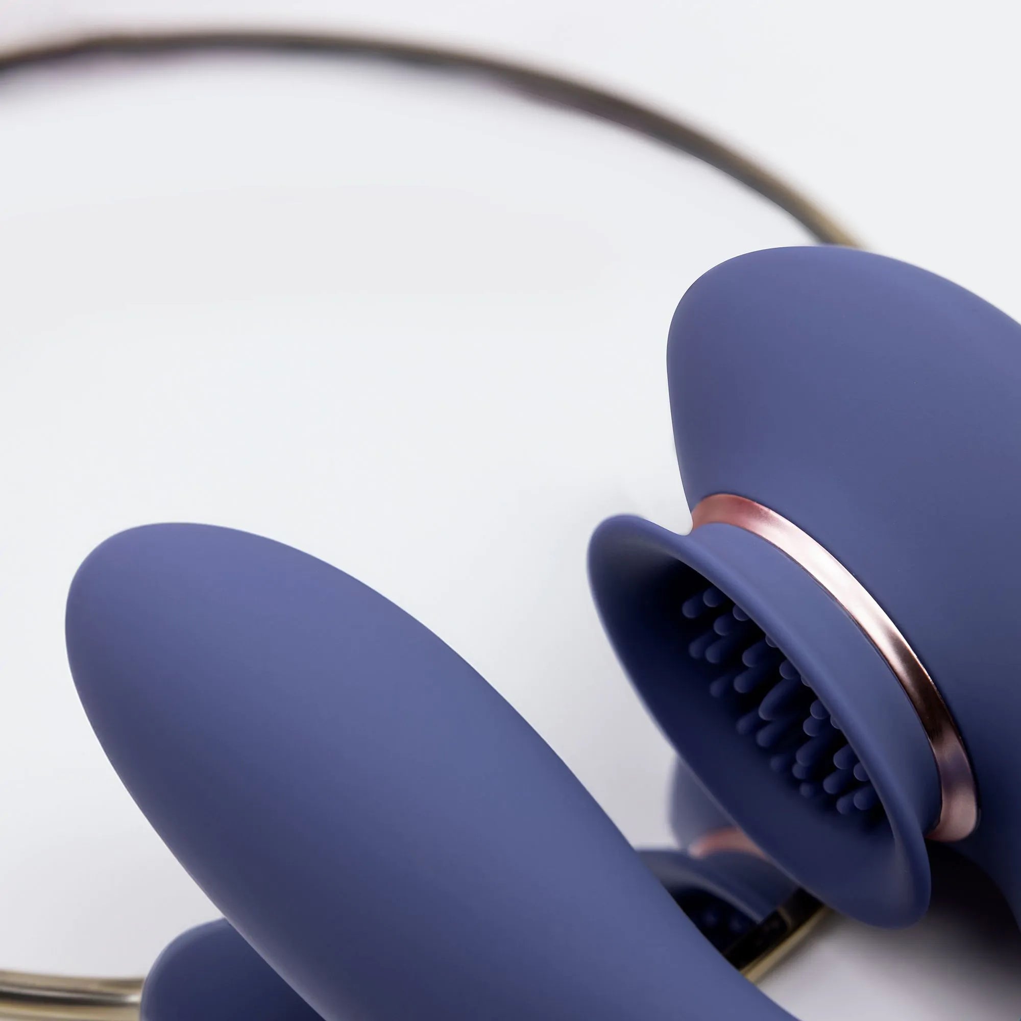 Lilla silikon sugevibrator med gullring og teksturert munnstykke.