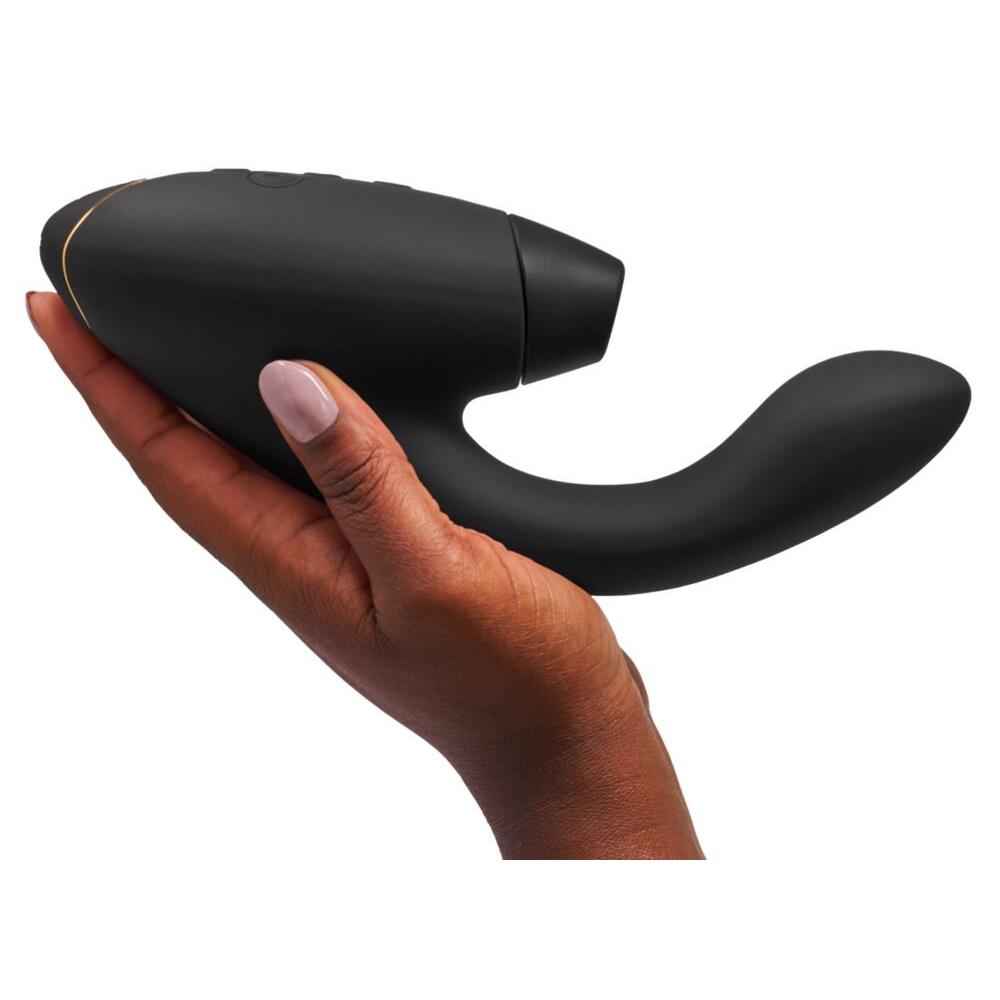 Womanizer Duo 2 svart klitoris- og G-punktstimulator holdt i en hånd, med gullkant.