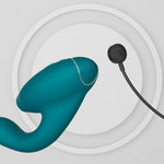 Dyp grønn Womanizer DUO 2 rabbitvibrator med Pleasure Air-teknologi og G-punktstimulering, vist med magnetisk lader.