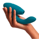 Hånd holder en dypgrønn Womanizer DUO 2 rabbitvibrator med Pleasure Air-teknologi og G-punktarm.